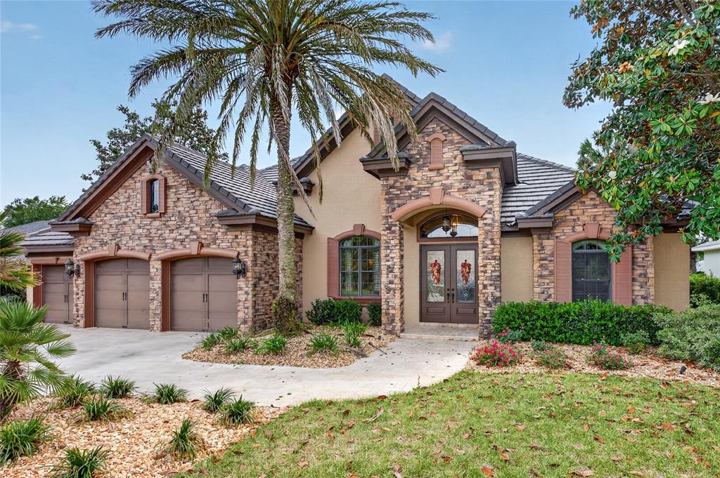A single-story house with a stone facade, a three-car garage, and a large palm tree — 6662 SW 179TH AVENUE ROAD, DUNNELLON, FL
