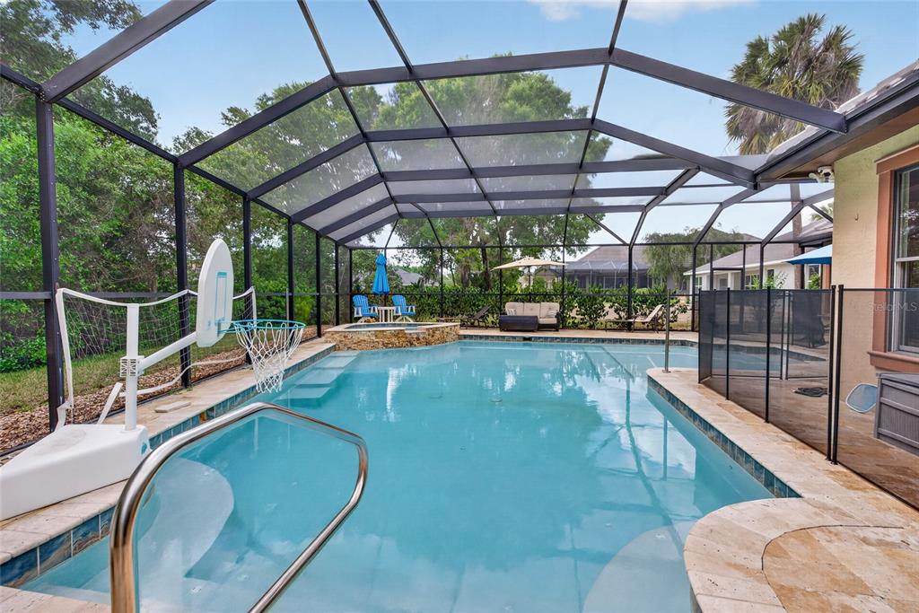 A screened-in swimming pool with a basketball hoop, hot tub, and patio furniture — 6662 SW 179TH AVENUE ROAD, DUNNELLON, FL