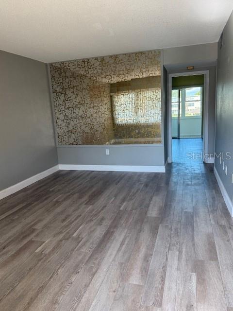 A room with wood-look flooring, a large decorative mirror wall, and a doorway to a balcony — 1051 79TH AVENUE N UNIT 212, ST PETERSBURG, FL