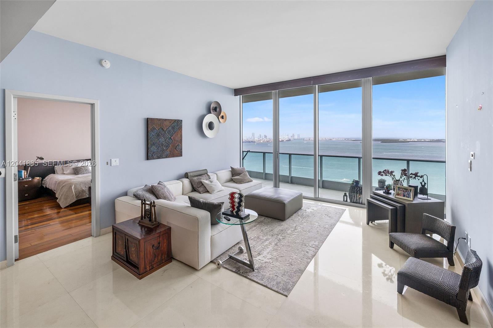 A living room with a white sectional sofa, light tile floors, and floor-to-ceiling ocean views — 1331 Brickell Bay Dr # 2909, Miami FL 33131, MIAMI, FL
