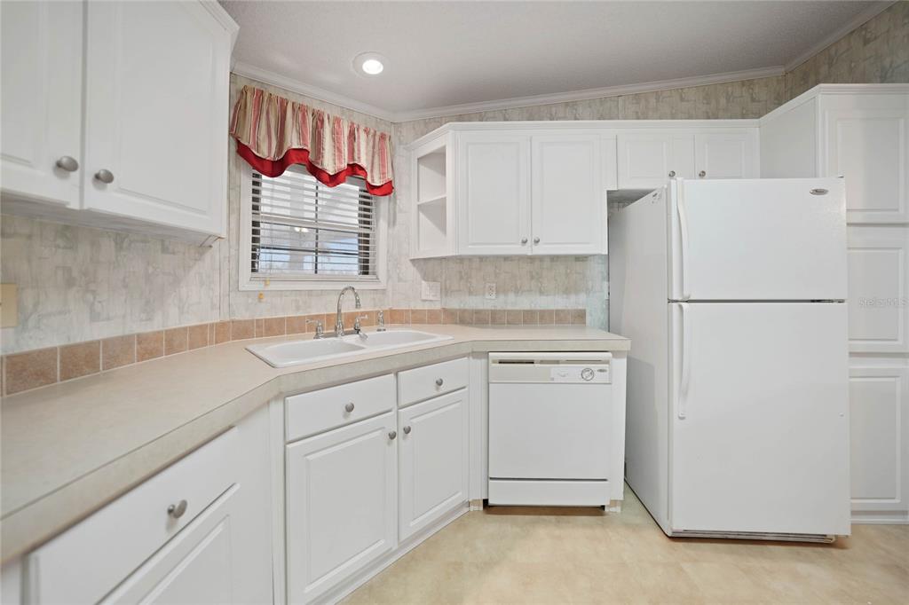 A kitchen features white cabinets, a white refrigerator, a dishwasher, and a double-basin sink — 2100 KINGS HIGHWAY UNIT 517, PORT CHARLOTTE, FL
