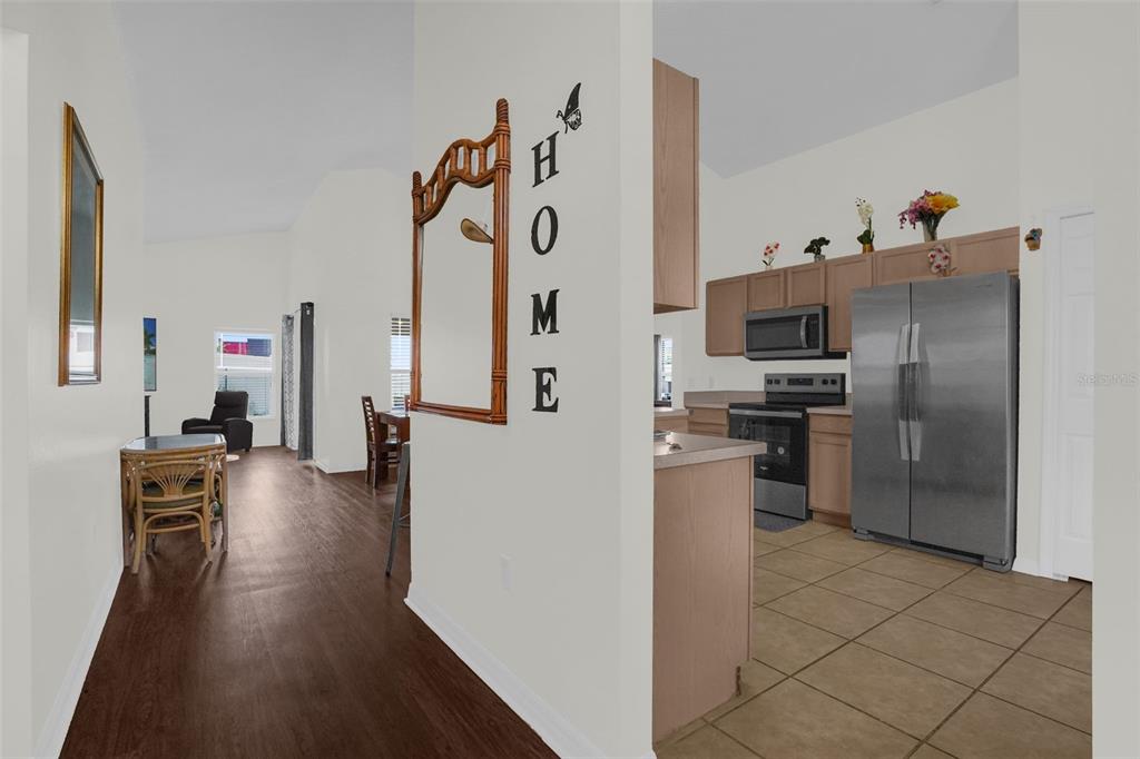A view from a hallway looking into a kitchen with tile floors and wood cabinets — 102 SAFFRON WAY, KISSIMMEE, FL