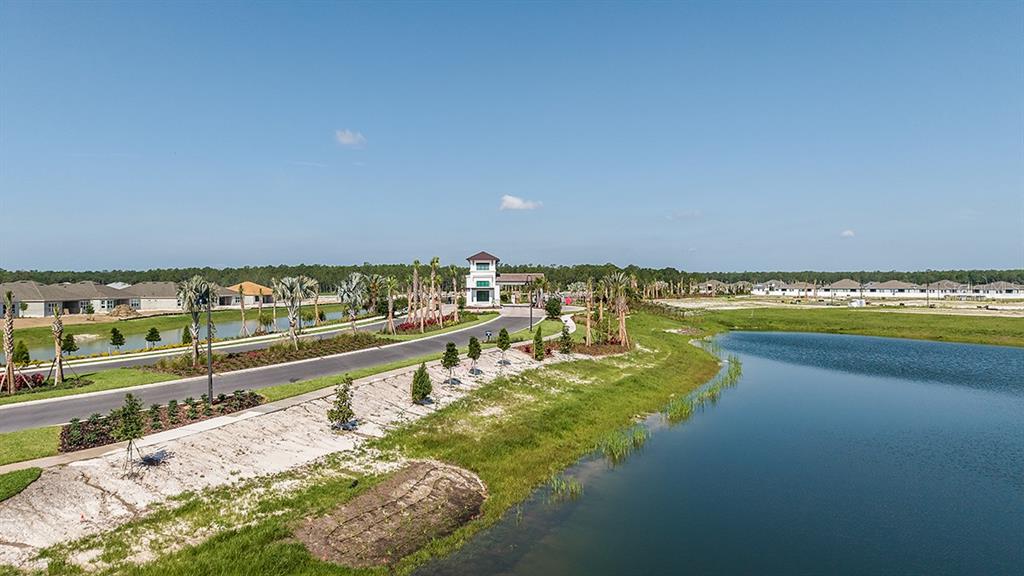 An aerial view shows a gated community entrance with a pond and new residential construction — 5446 CROWN POINT ROAD, KISSIMMEE, FL