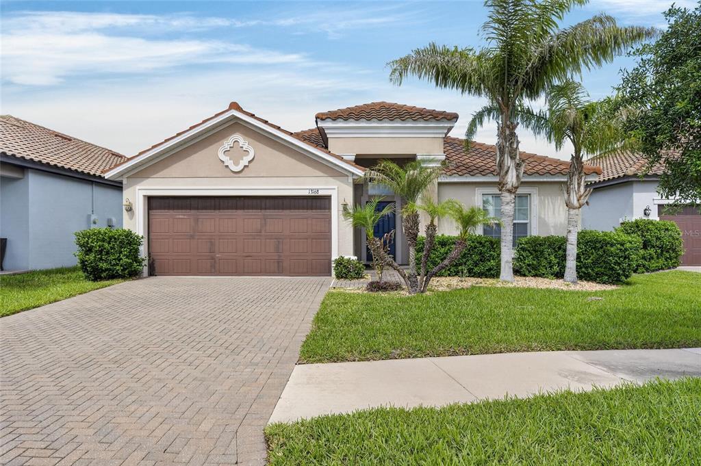 A single-story house with a brown garage door, tiled roof, and palm trees in front — 13168 GREEN VIOLET DRIVE, RIVERVIEW, FL