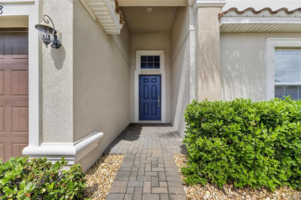 A blue front door is centered at the end of a stone walkway and entryway — 13168 GREEN VIOLET DRIVE, RIVERVIEW, FL
