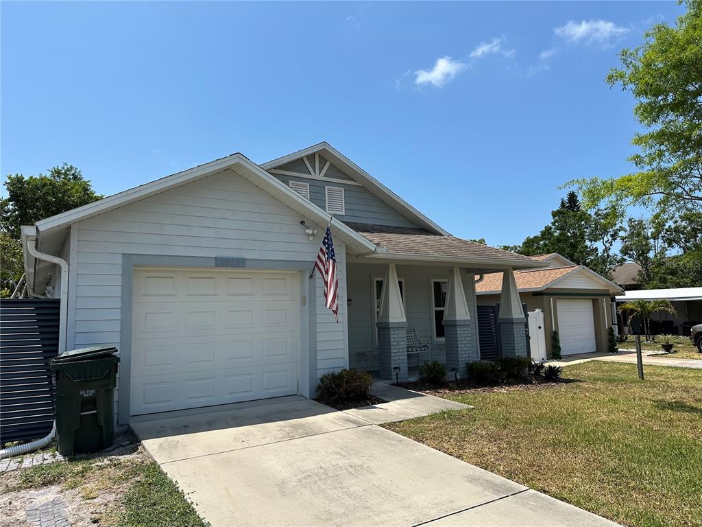 A light blue single-story house with a garage, front porch, and an American flag — 1119 BEVERLY AVENUE, LARGO, FL