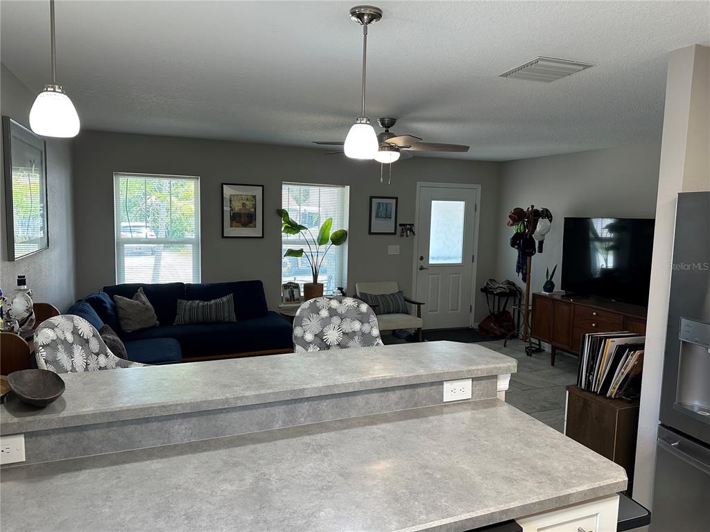 A kitchen counter overlooks a living room with a blue sectional sofa and television — 1119 BEVERLY AVENUE, LARGO, FL