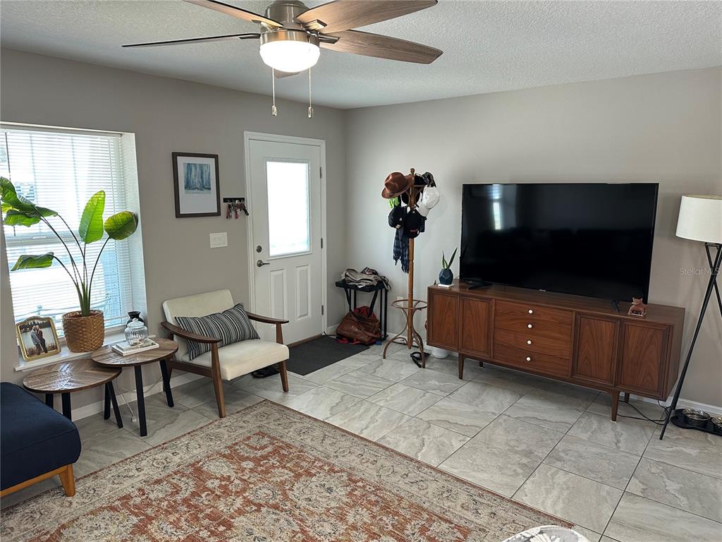 A living room features tile flooring, a mid-century modern media console, and a ceiling fan — 1119 BEVERLY AVENUE, LARGO, FL