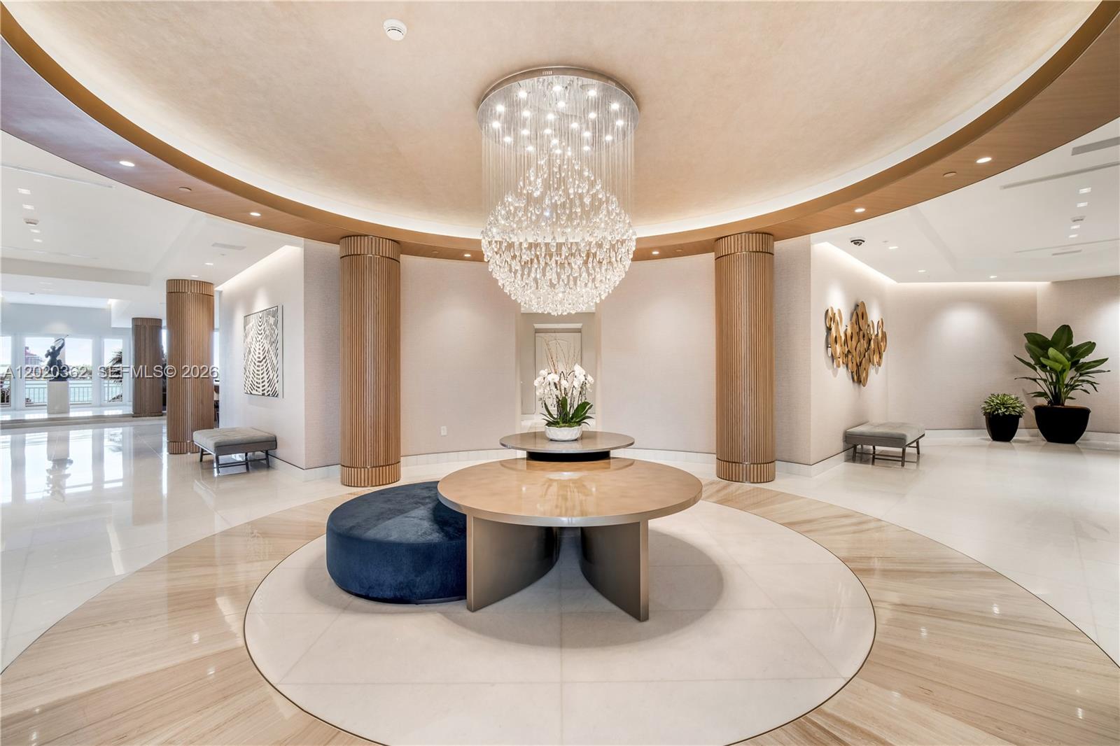 A modern lobby features a large crystal chandelier, circular tables, and fluted wooden columns — 888 Brickell Key Dr # 1612, Miami FL 33131, MIAMI, FL