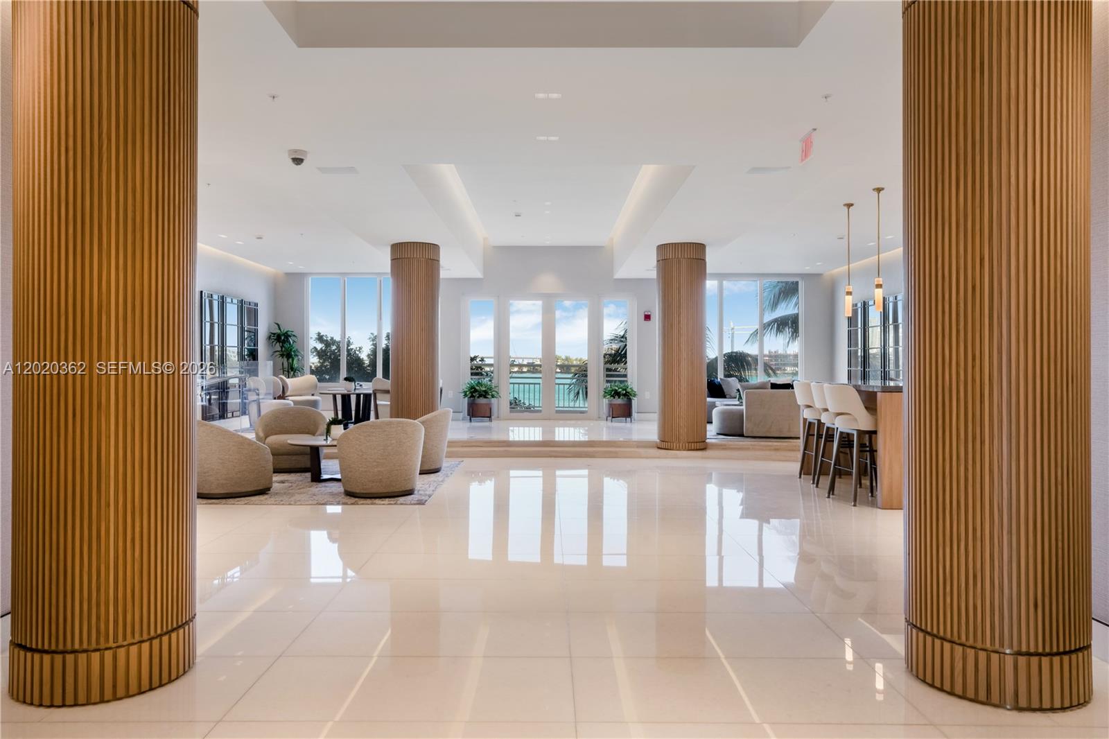 A spacious lobby features large fluted wooden columns, white tile flooring, and floor-to-ceiling windows — 888 Brickell Key Dr # 1612, Miami FL 33131, MIAMI, FL