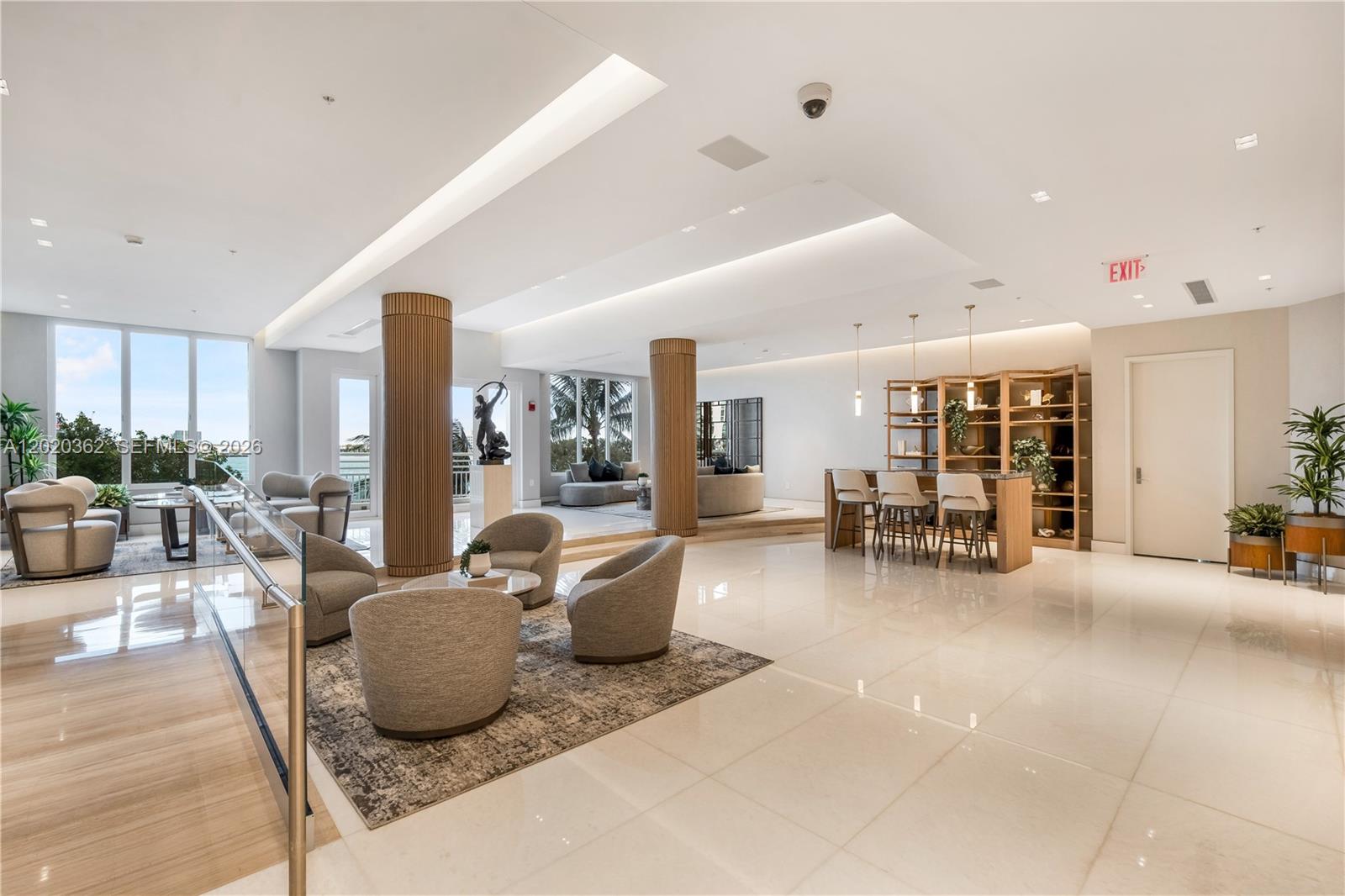 A modern, open-concept lobby features marble floors, wooden columns, lounge seating, and a bar area — 888 Brickell Key Dr # 1612, Miami FL 33131, MIAMI, FL