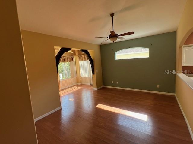 An empty living room features wood-look flooring, a ceiling fan, and a decorative arched entryway — 77 VERANDA WAY, PALM COAST, FL