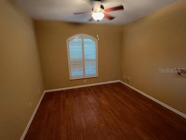 An empty bedroom features tan walls, wood-look flooring, a ceiling fan, and an arched window — 77 VERANDA WAY, PALM COAST, FL
