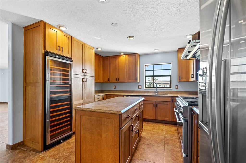 A kitchen features wood cabinetry, a granite-topped island, stainless steel appliances, and tile flooring — 3726 S ATLANTIC AVENUE, NEW SMYRNA BEACH, FL
