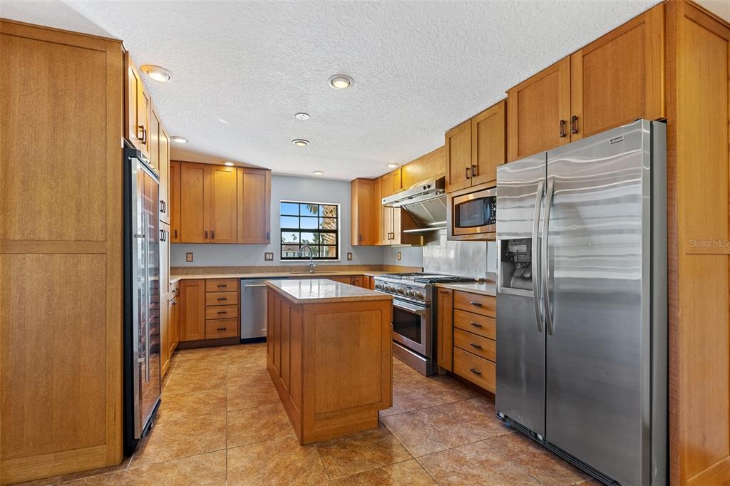 A kitchen with wood cabinets, stainless steel appliances, a center island, and tile flooring — 3726 S ATLANTIC AVENUE, NEW SMYRNA BEACH, FL