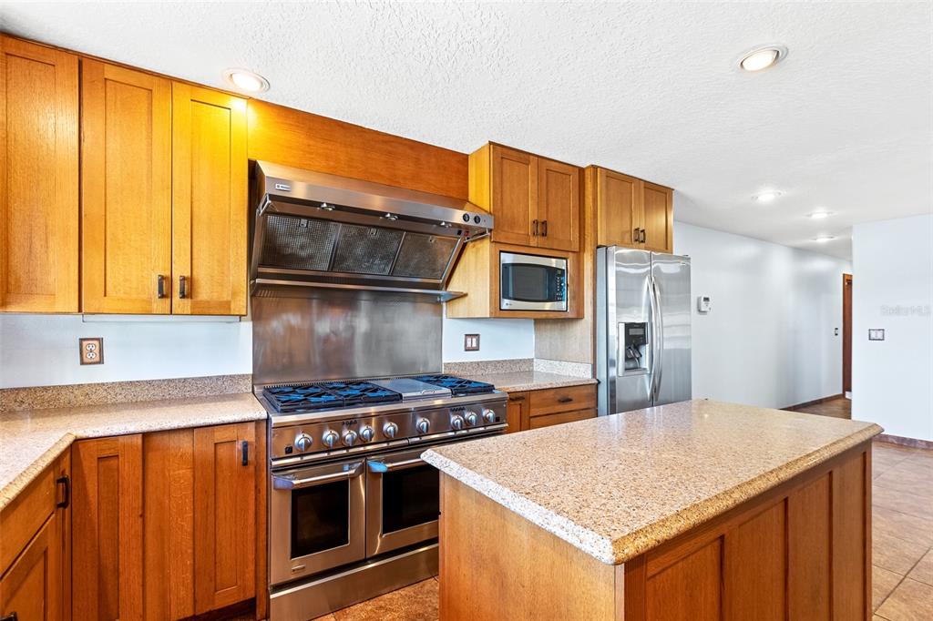 A kitchen features wood cabinets, stainless steel appliances, a gas range, and granite countertops — 3726 S ATLANTIC AVENUE, NEW SMYRNA BEACH, FL