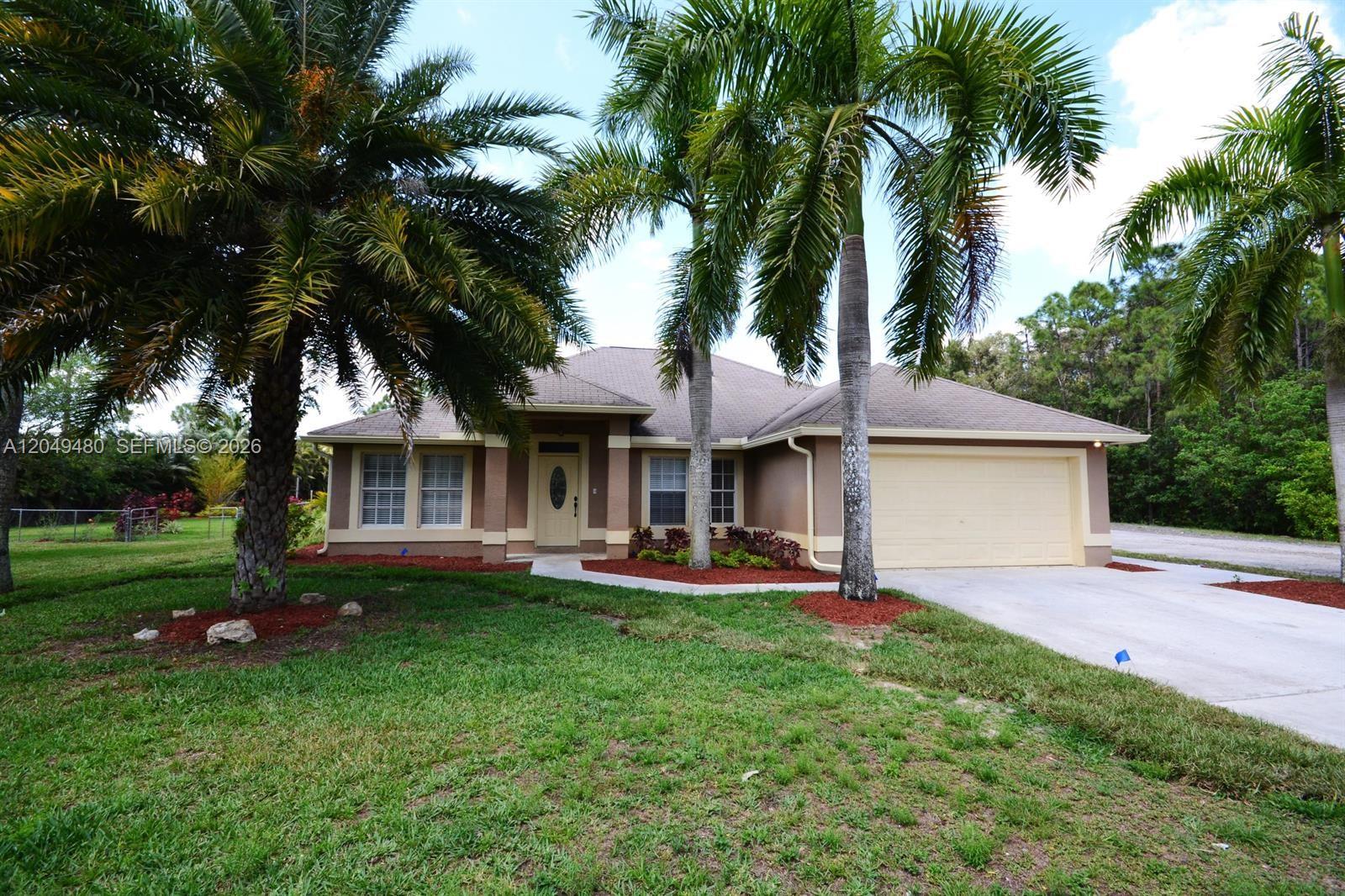 A single-story house with a beige stucco exterior, a two-car garage, and palm trees — 17569 N 89th Pl N, Loxahatchee FL 33470, LOXAHATCHEE, FL
