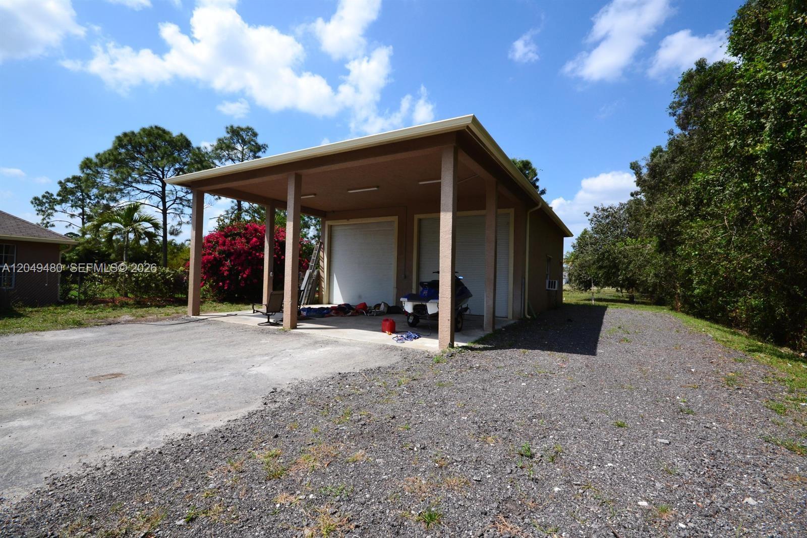 A detached two-car garage with a covered patio area sits on a gravel lot — 17569 N 89th Pl N, Loxahatchee FL 33470, LOXAHATCHEE, FL