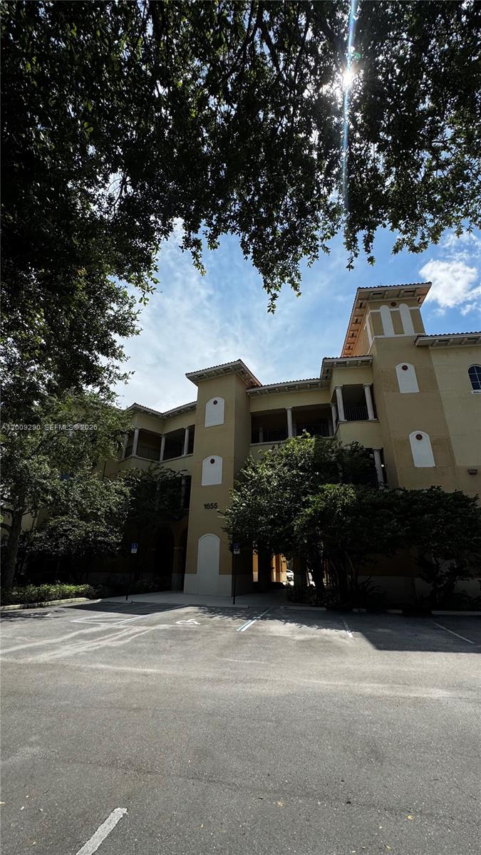 A multi-story tan stucco apartment building with a parking lot in the foreground — 1655 N Commerce Pkwy # 301, Weston FL 33326, WESTON, FL