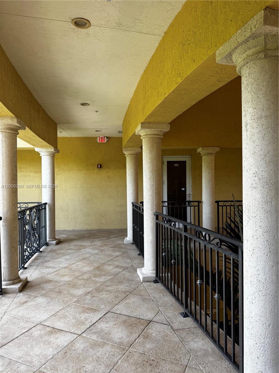 A covered outdoor walkway features stone-tiled flooring, decorative columns, and black metal railings — 1655 N Commerce Pkwy # 301, Weston FL 33326, WESTON, FL