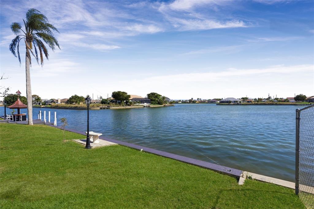 A grassy backyard overlooks a canal with a palm tree, a gazebo, and a dock — 29 SE 10TH AVENUE, CAPE CORAL, FL