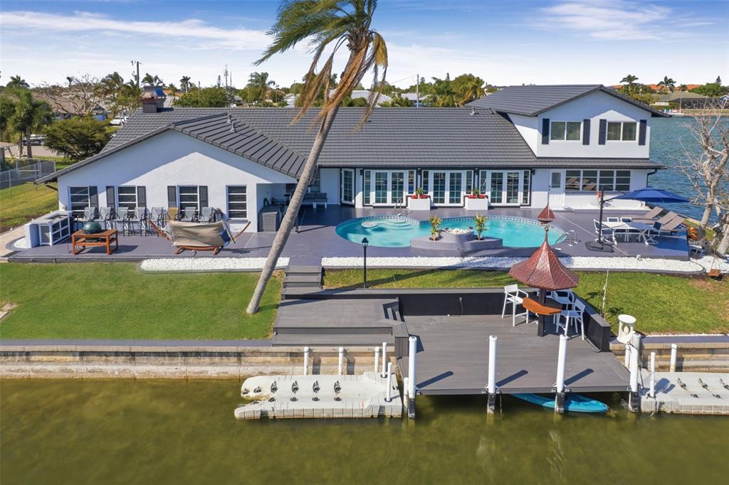 An aerial view of a waterfront home featuring a pool, deck, and private boat dock — 29 SE 10TH AVENUE, CAPE CORAL, FL