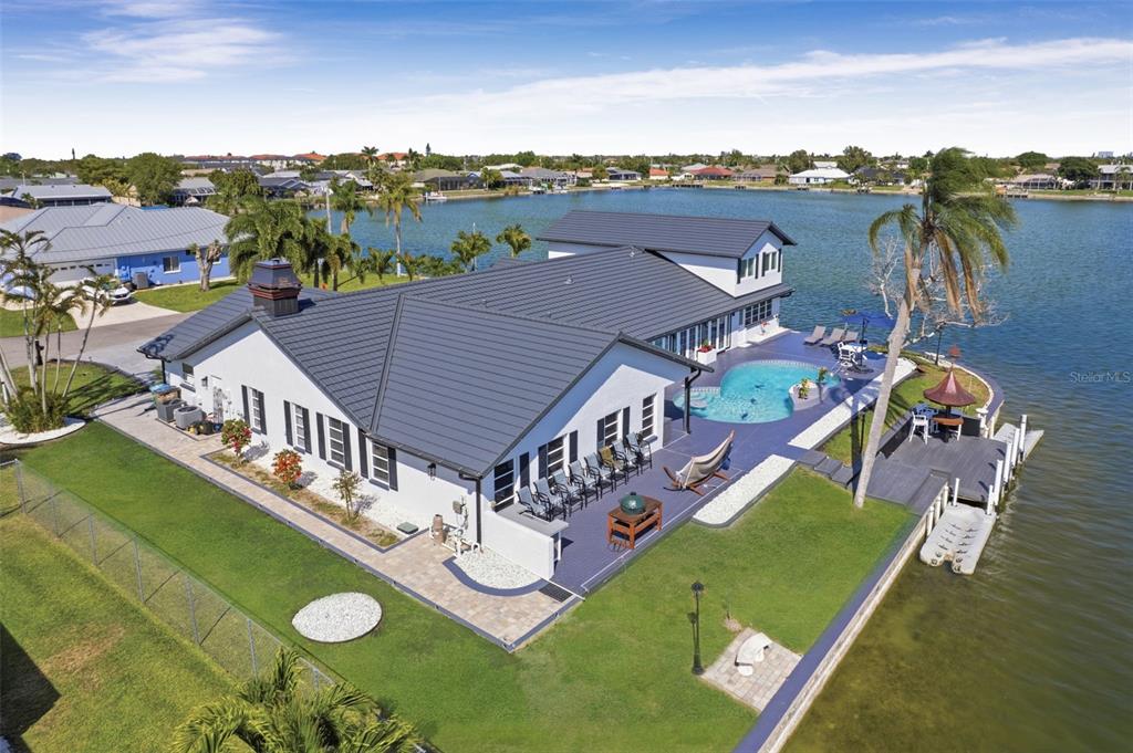 An aerial view of a waterfront house with a dark roof, pool, and private dock — 29 SE 10TH AVENUE, CAPE CORAL, FL
