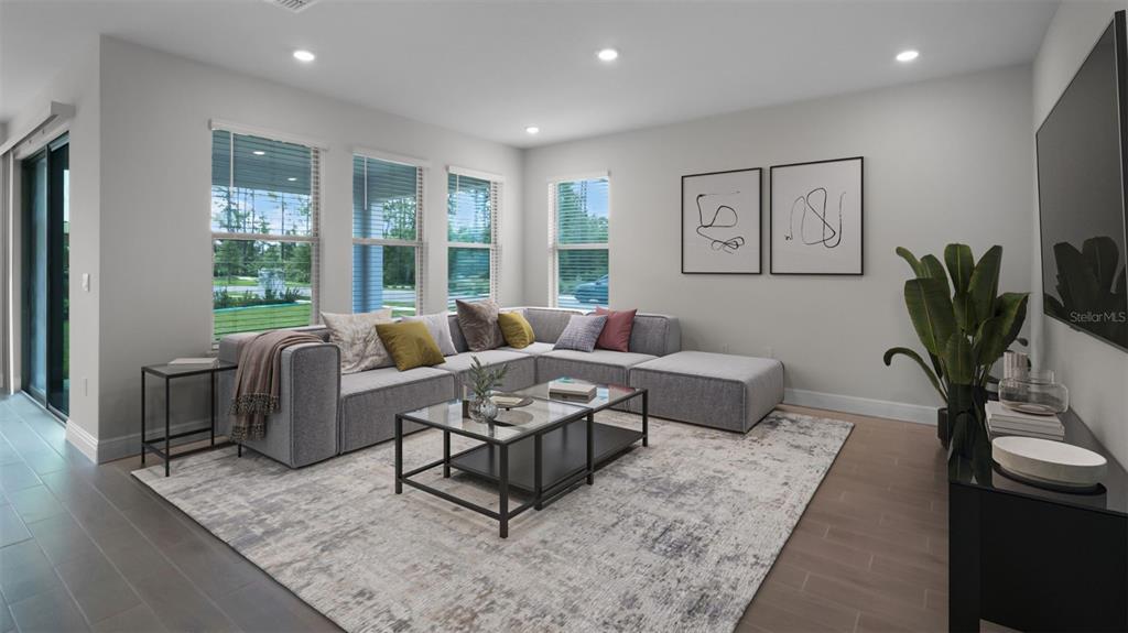 A modern living room features a gray sectional sofa, glass coffee tables, and large windows — 11253 HOLLOW BAY DRIVE, WINTER GARDEN, FL