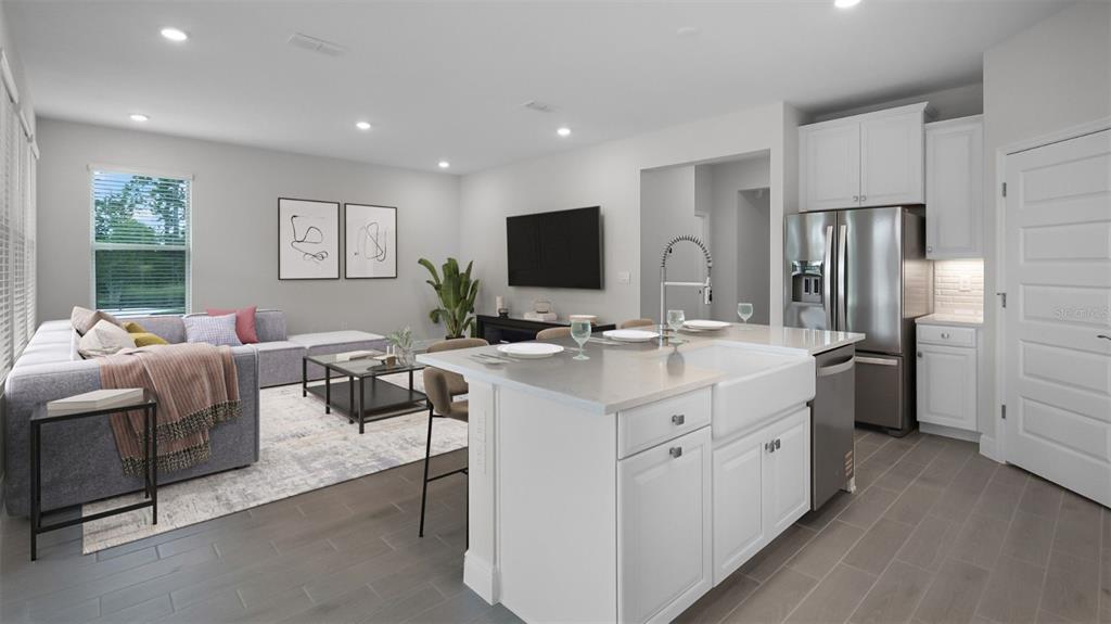 An open-concept kitchen with a farmhouse sink and island overlooks a living room with furniture — 11253 HOLLOW BAY DRIVE, WINTER GARDEN, FL