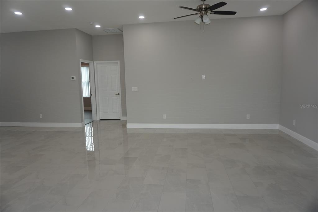 A spacious room features light gray walls, white trim, and large, glossy, light-colored floor tiles — 12572 TREE STREET, LARGO, FL