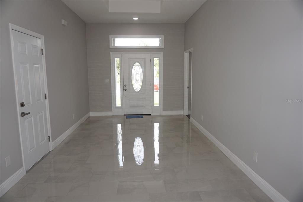 A bright entryway features light gray walls, glossy tile flooring, and a white front door — 12572 TREE STREET, LARGO, FL