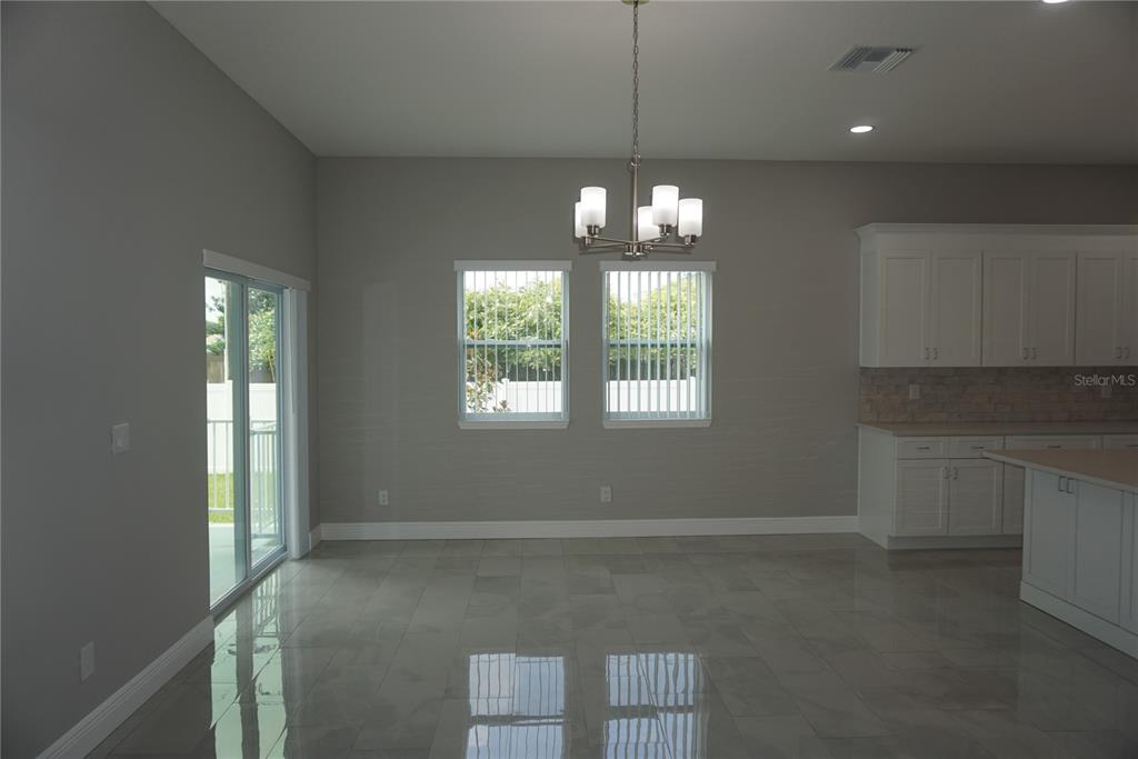 A dining area with gray walls, tile flooring, a chandelier, and sliding glass patio doors — 12572 TREE STREET, LARGO, FL