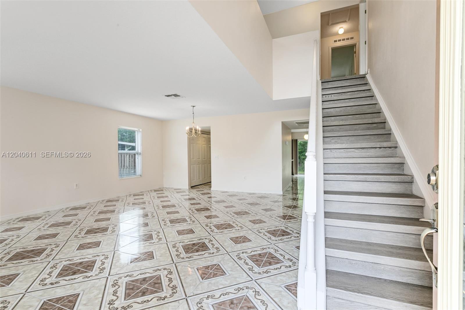 An entryway features a staircase with wood-look treads and a room with patterned tile flooring — 12096 Prospect Creek Dr # 0, Jacksonville FL 32218, JACKSONVILLE, FL