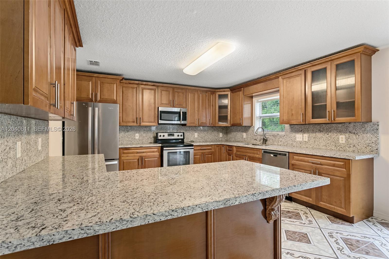 A kitchen features wood cabinets, granite countertops, stainless steel appliances, and tiled flooring — 12096 Prospect Creek Dr # 0, Jacksonville FL 32218, JACKSONVILLE, FL