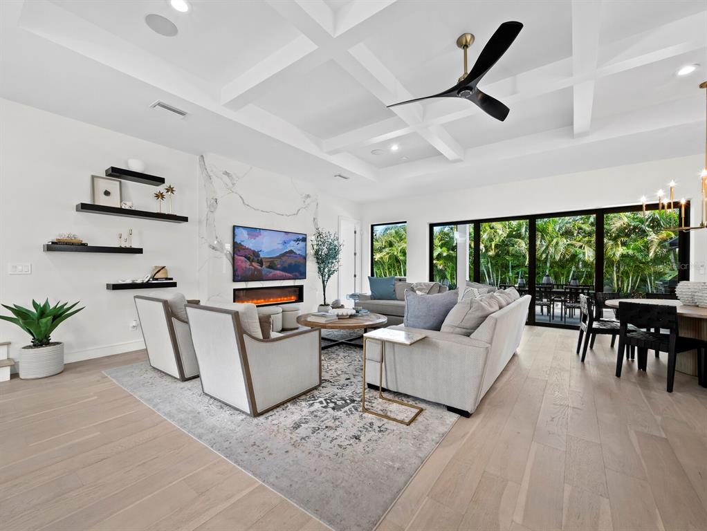 A modern living room features a coffered ceiling, marble fireplace, and large sliding glass doors — 1717 ALTA VISTA STREET, SARASOTA, FL
