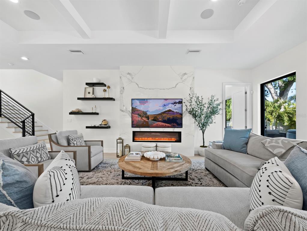 A living room features a marble fireplace, wall-mounted television, floating shelves, and neutral furniture — 1717 ALTA VISTA STREET, SARASOTA, FL