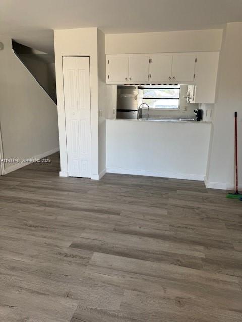 A kitchen with white cabinets and a pass-through window overlooks a room with wood-look flooring — 13404 SW 62nd St # 101L, Miami FL 33183, MIAMI, FL