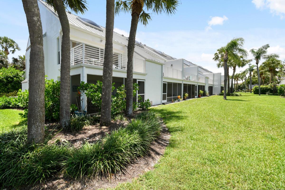 A white multi-story townhouse with screened-in porches and balconies sits beside a grassy lawn — 1605 S Us Highway 1 # 214, Jupiter FL 33477, JUPITER, FL