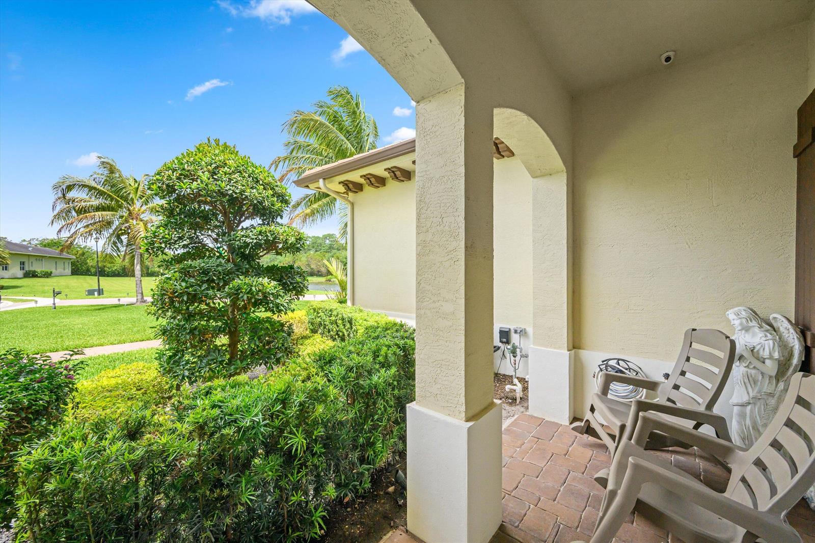 A covered patio features brick pavers, two plastic chairs, an angel statue, and garden views — 7336 Sisken Terrace, Lake Worth FL 33463, LAKE WORTH, FL
