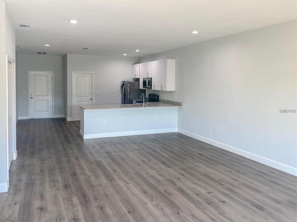 An open-concept kitchen with white cabinets and a breakfast bar overlooks a living area — 9163 AGATE STREET, PORT CHARLOTTE, FL