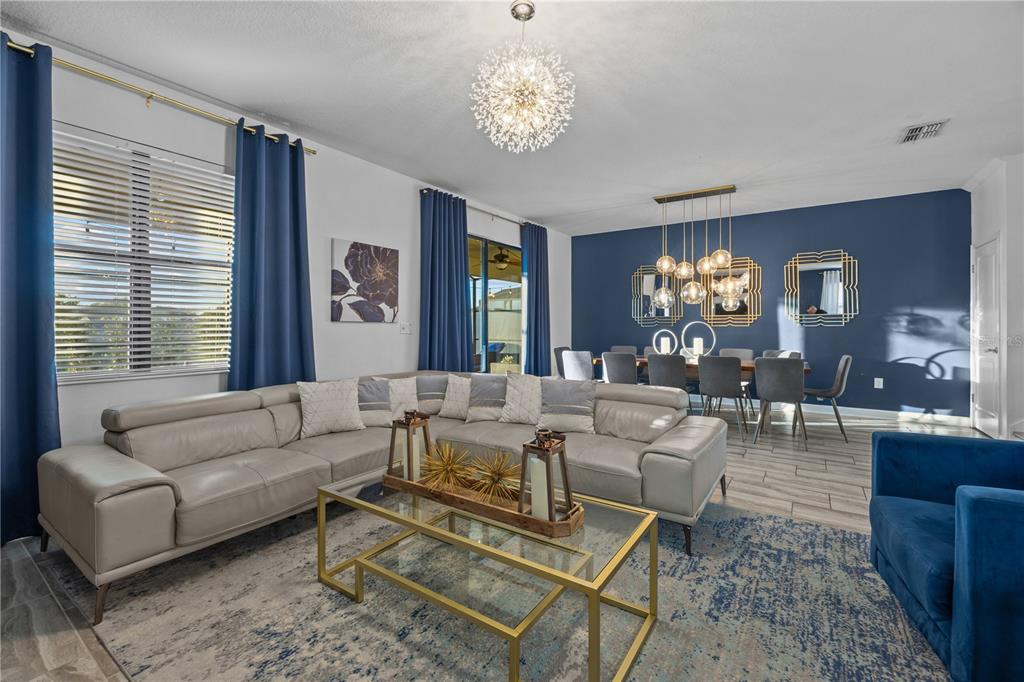 A living and dining area features a grey sectional sofa, blue curtains, and blue walls — 1314 BIRDIE WAY, DAVENPORT, FL