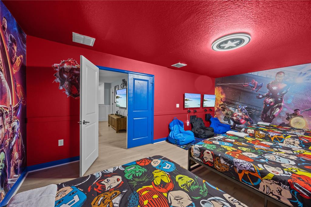 A themed bedroom features Marvel character wall murals, red walls, two beds, and gaming chairs — 1314 BIRDIE WAY, DAVENPORT, FL
