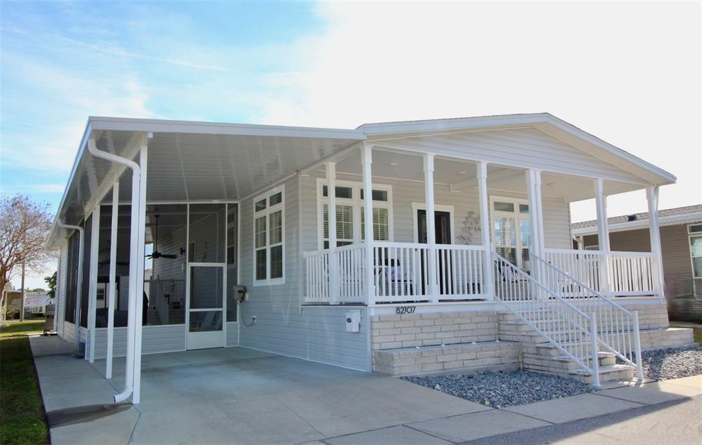 A light gray manufactured home features a covered carport, a screened porch, and a front deck — 82107 A STREET N UNIT 107, PINELLAS PARK, FL