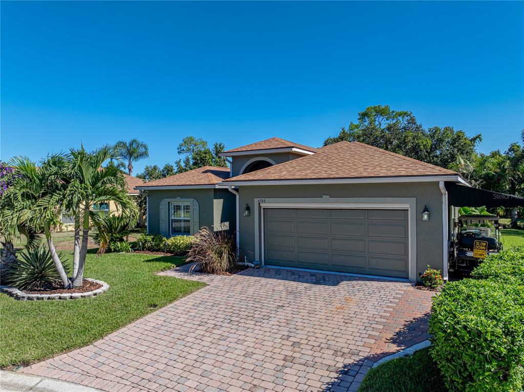 A single-story house with a paved driveway, two-car garage, and palm trees in the yard — 4184 ABERDEEN LANE, LAKE WALES, FL