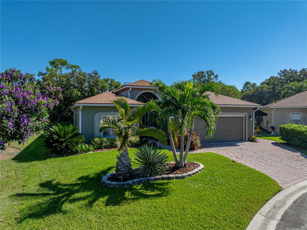 A single-story house with a tan exterior, a paved driveway, and palm trees in the yard — 4184 ABERDEEN LANE, LAKE WALES, FL