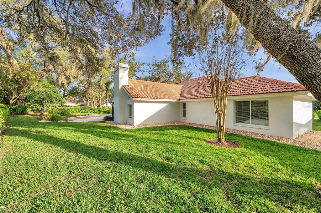 The exterior of a white house with a red tile roof and a brick chimney — 5473 BLUE HERON LANE, WESLEY CHAPEL, FL