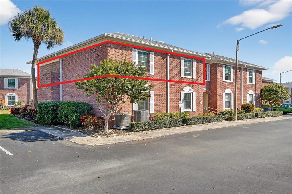 A two-story brick apartment building with a red outline highlighting the upper-level exterior wall — 3910 37TH STREET S UNIT 39, ST PETERSBURG, FL