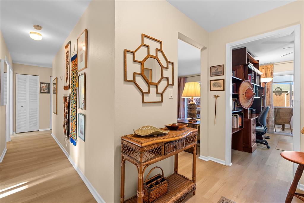 A hallway with light wood flooring leads to a home office and a living area — 3910 37TH STREET S UNIT 39, ST PETERSBURG, FL
