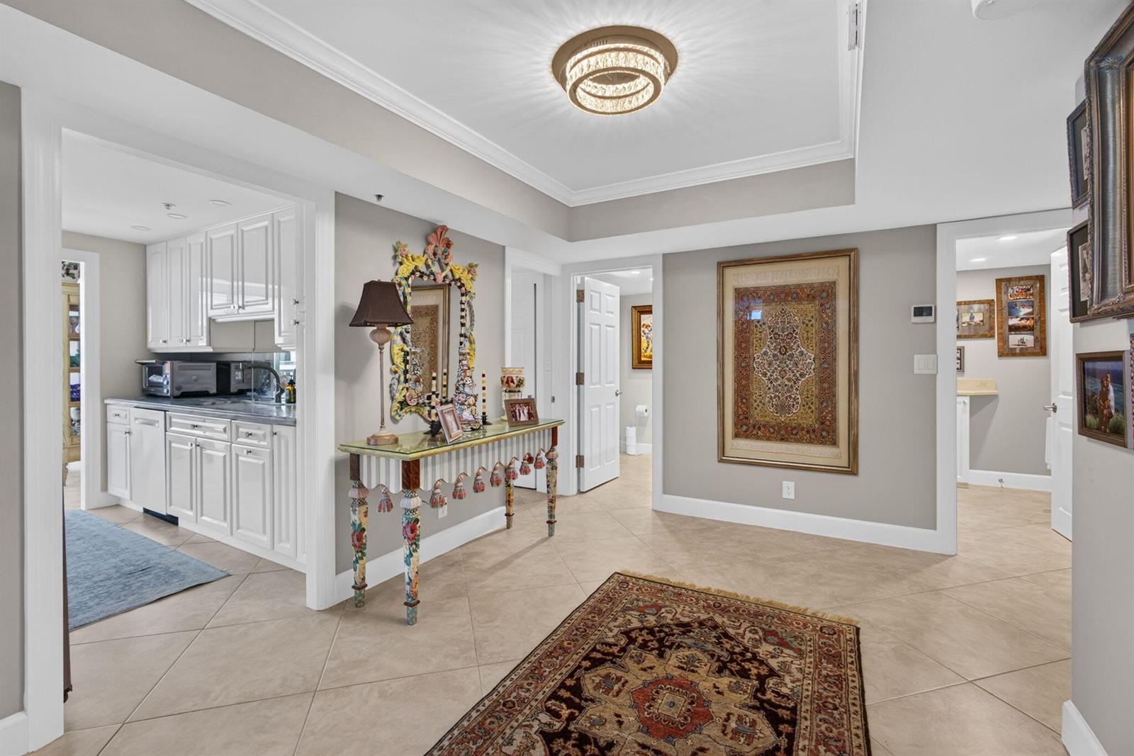 A tiled hallway features a decorative console table, a large framed tapestry, and a chandelier — 5280 N Ocean Drive # 3a, Singer Island FL 33404, SINGER ISLAND, FL
