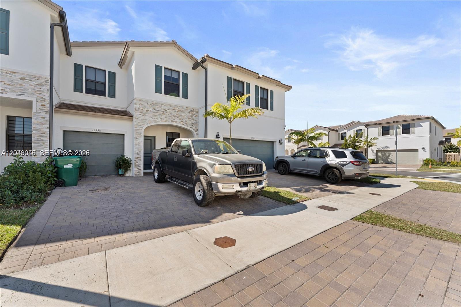 A two-story residential building with a paved driveway, a pickup truck, and an SUV — 12958 SW 231st St, Miami FL 33170, MIAMI, FL
